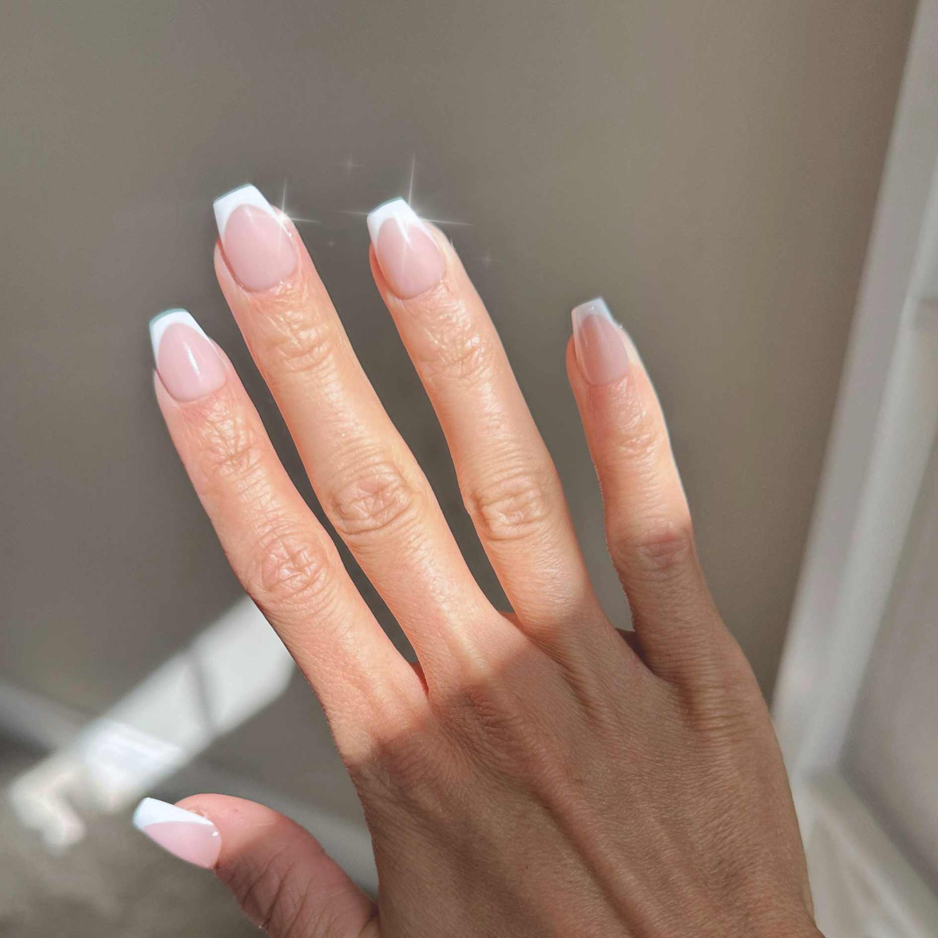 Reusable, handmade press on nails in a beautiful standard french design with a soft nude base. shown in extra short coffin by hannalee marie.