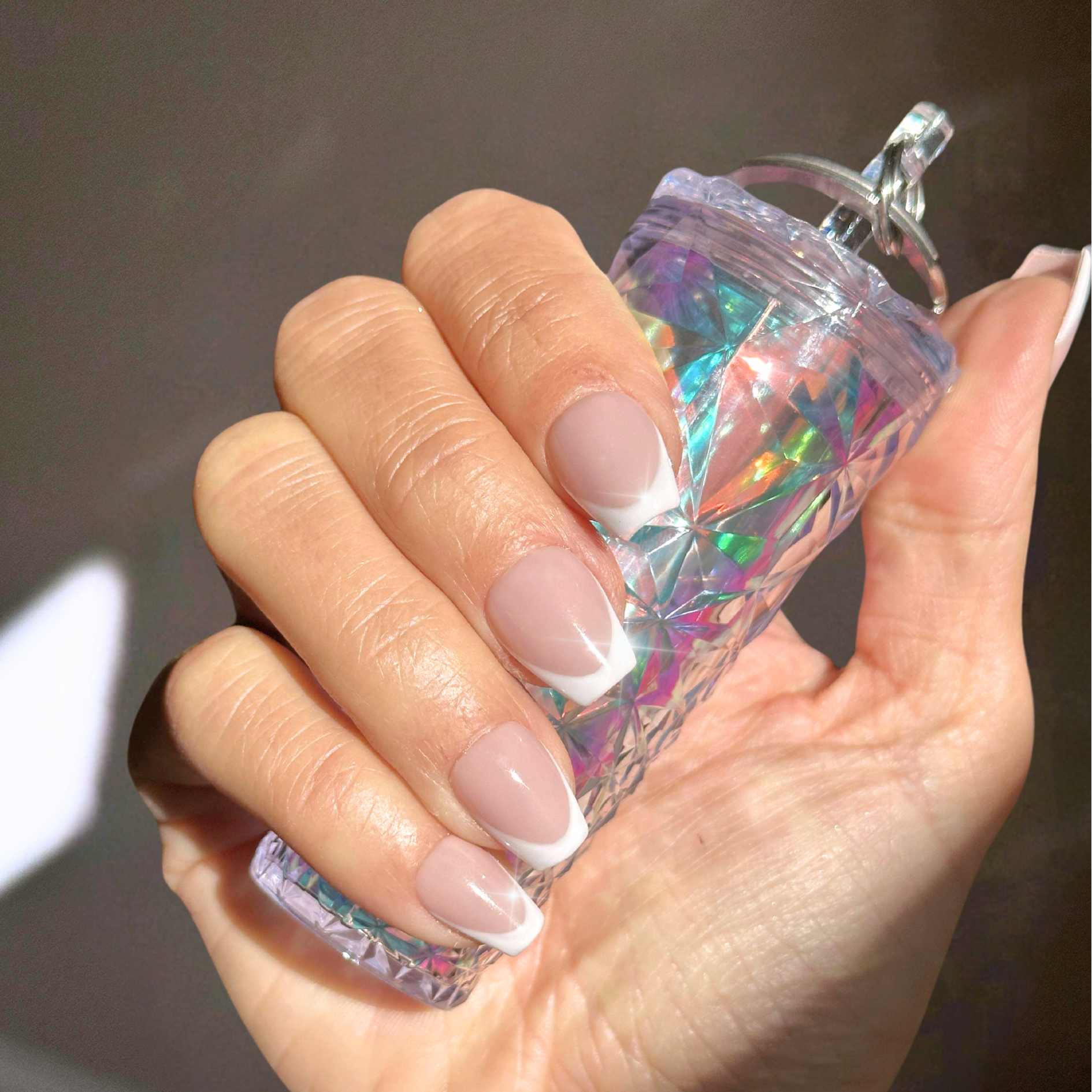 Reusable, handmade press on nails in a beautiful standard french design with a soft nude base. shown in extra short coffin by hannalee marie.