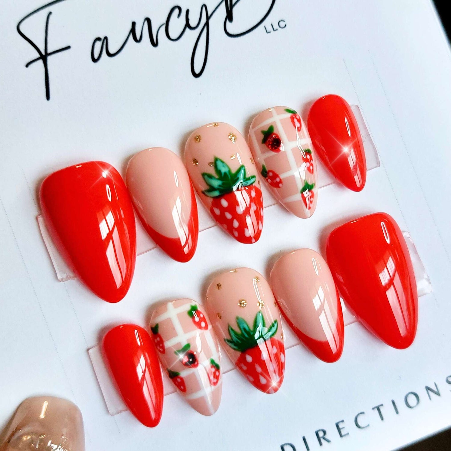 custom strawberry nails, summery fruit nails with strawberries and bright red french accents, gold glitter, and short almond shape from FancyB handmade nails.