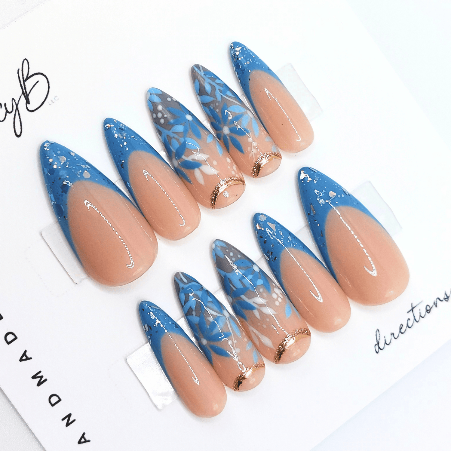 Custom press on nails in medium stiletto with nude base and blue leaves and florals, hand painted flower nails from FancyB.