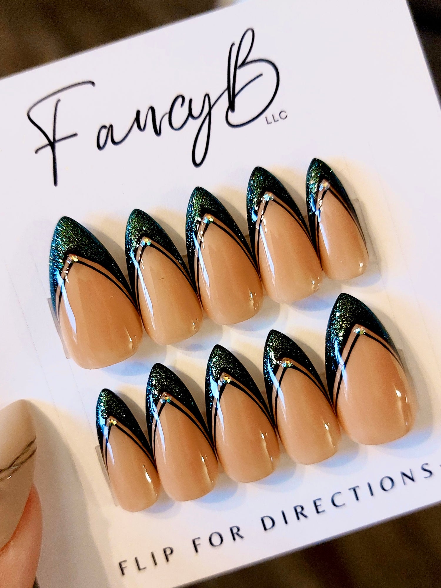 Custom press on nails with glitter green french tip and nude base, black lines, and gems. Fancyb luxury nails.