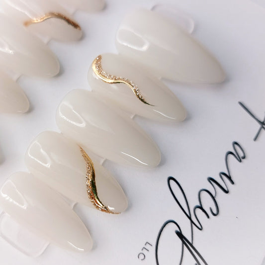 24 karat gold, gold chrome, milky white, and gold glitter press on nails on milky white in short stiletto shape.