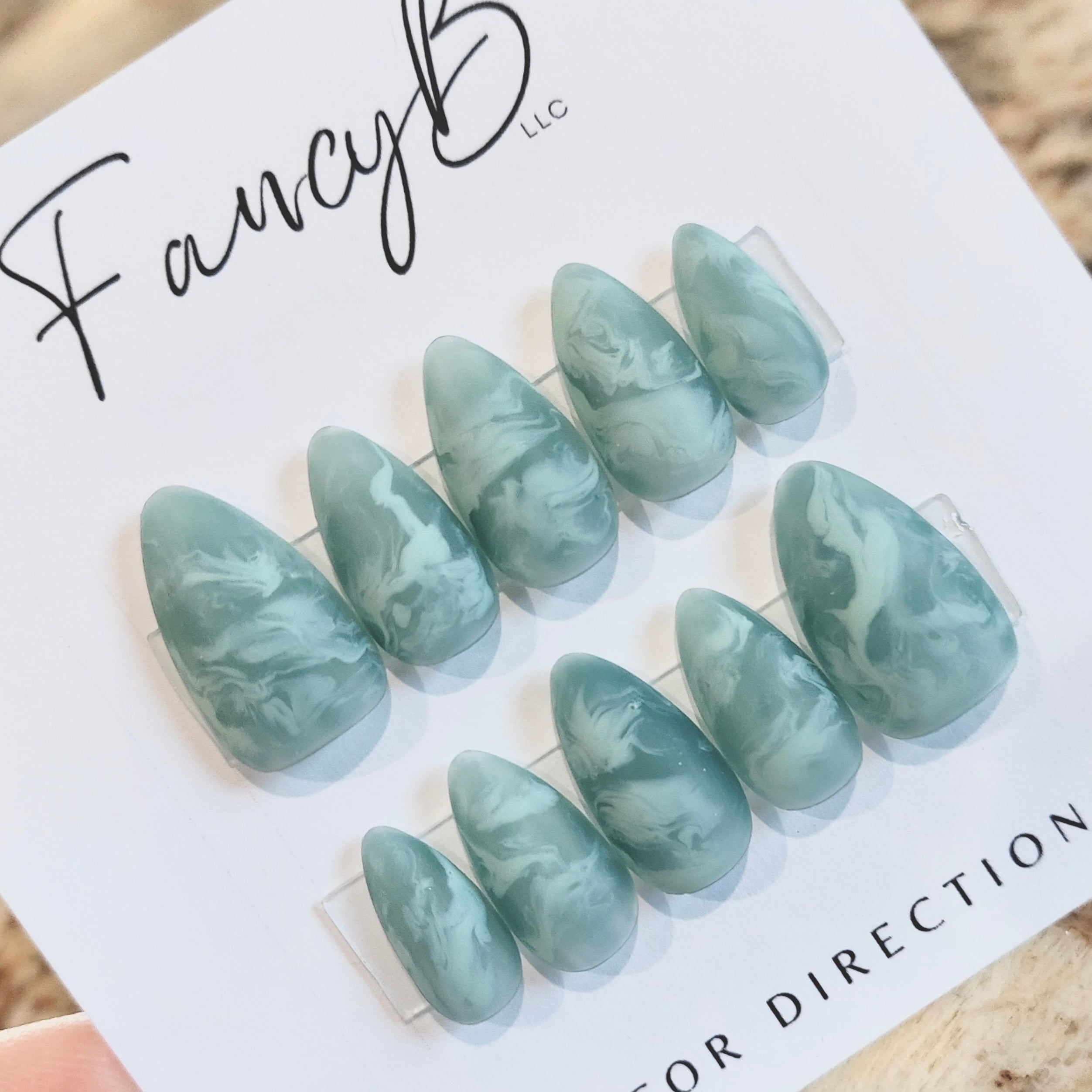 Custom press on nails with seafoam green smoky swirls and marble design, sea glass nail design, ocean waves all on a short almond shape. Fancyb Nails.