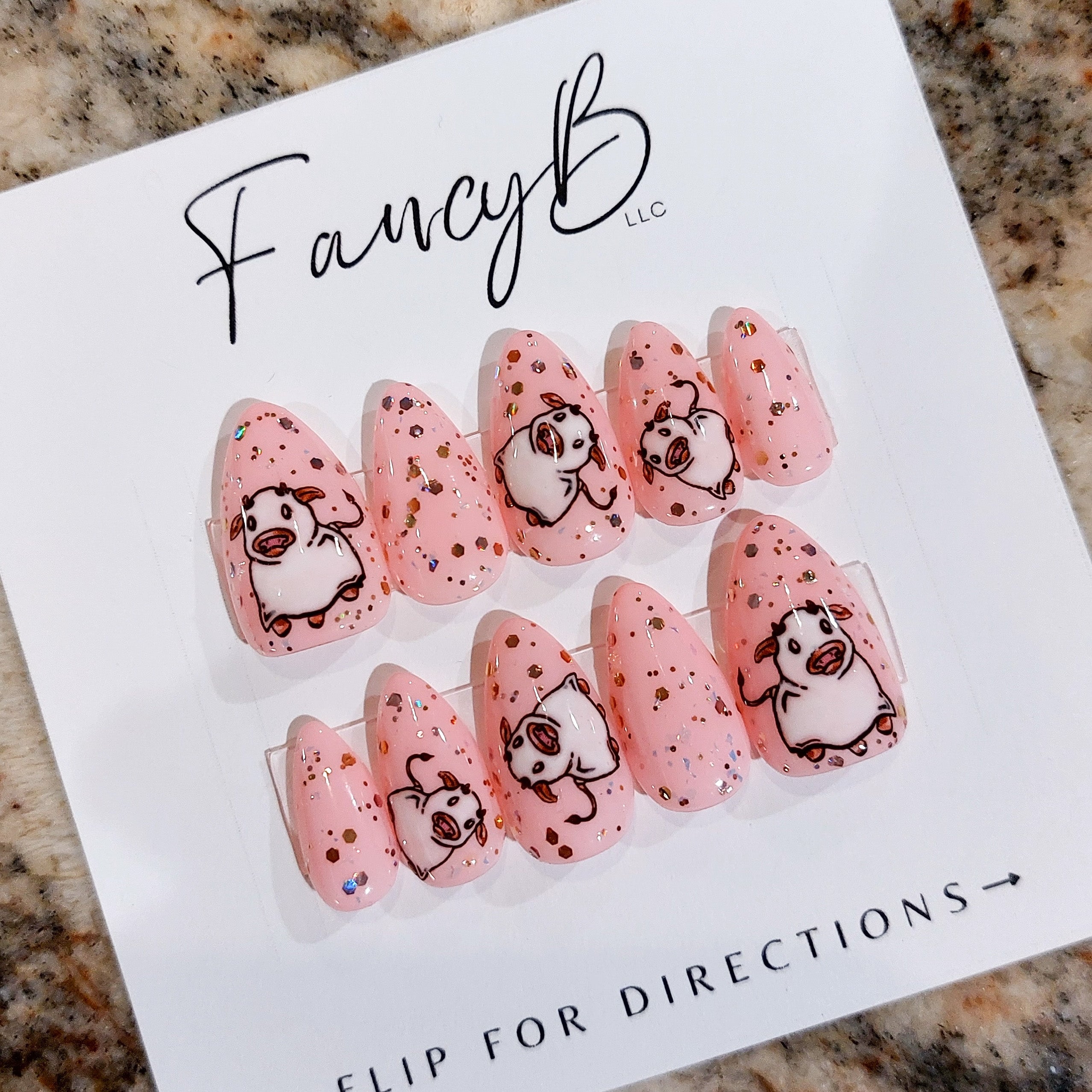 Custom press on nails with light pink, glitter, and ghost cows on a short almond shape. FancyB Nails.