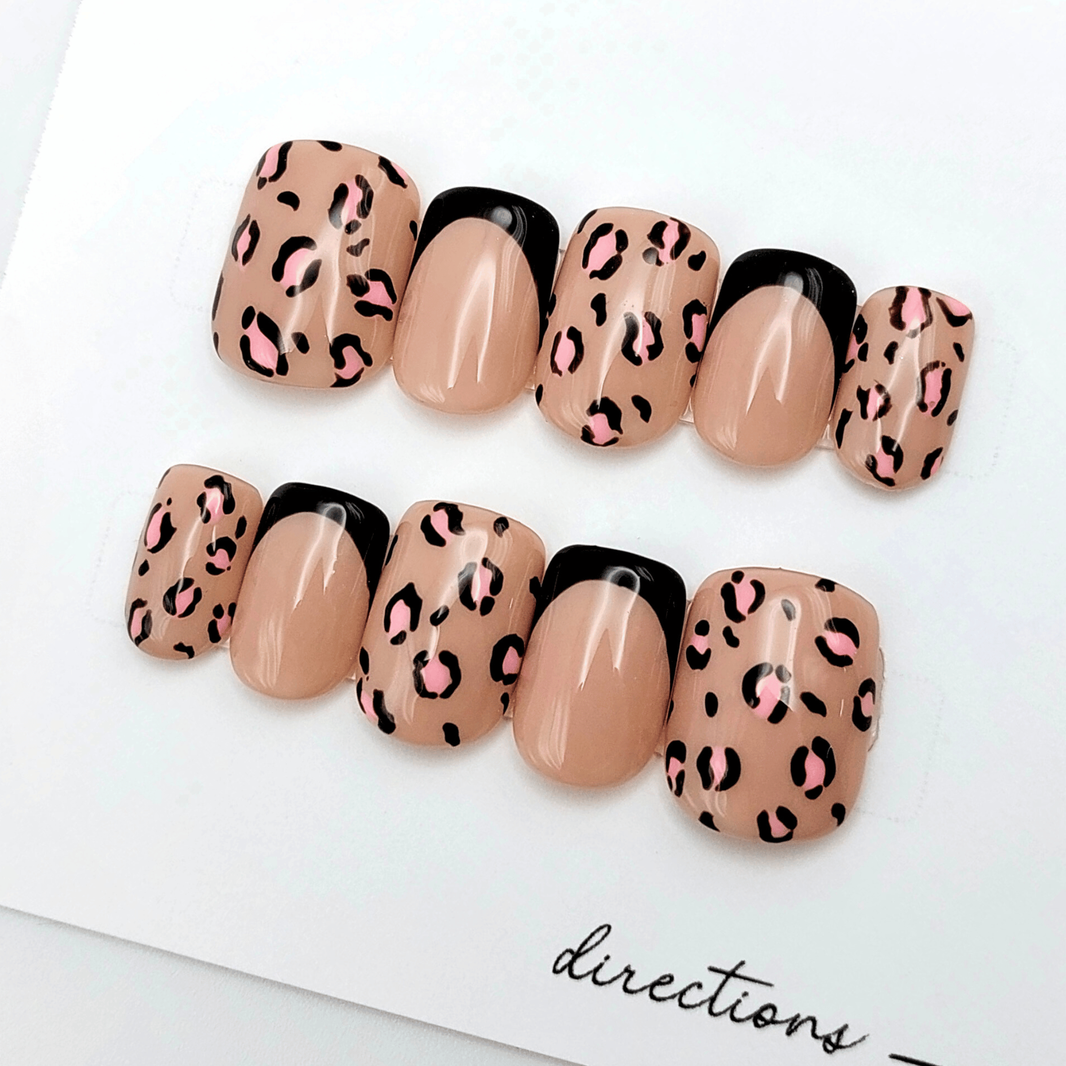 custom leopard press on nails with nude base and pink leopard spots on short squoval nails.