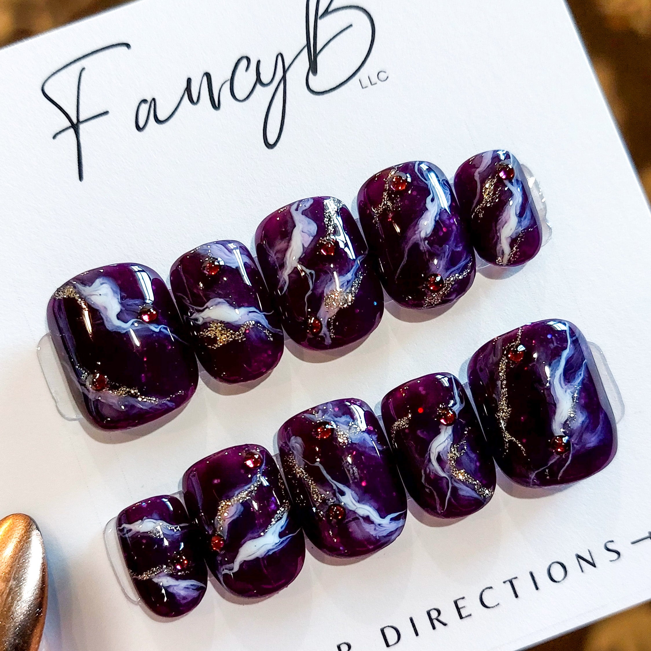 Custom marble press on nails, purple marble design with glitter and purple amethyst gems on a short square nail shape. FancyB Nails.