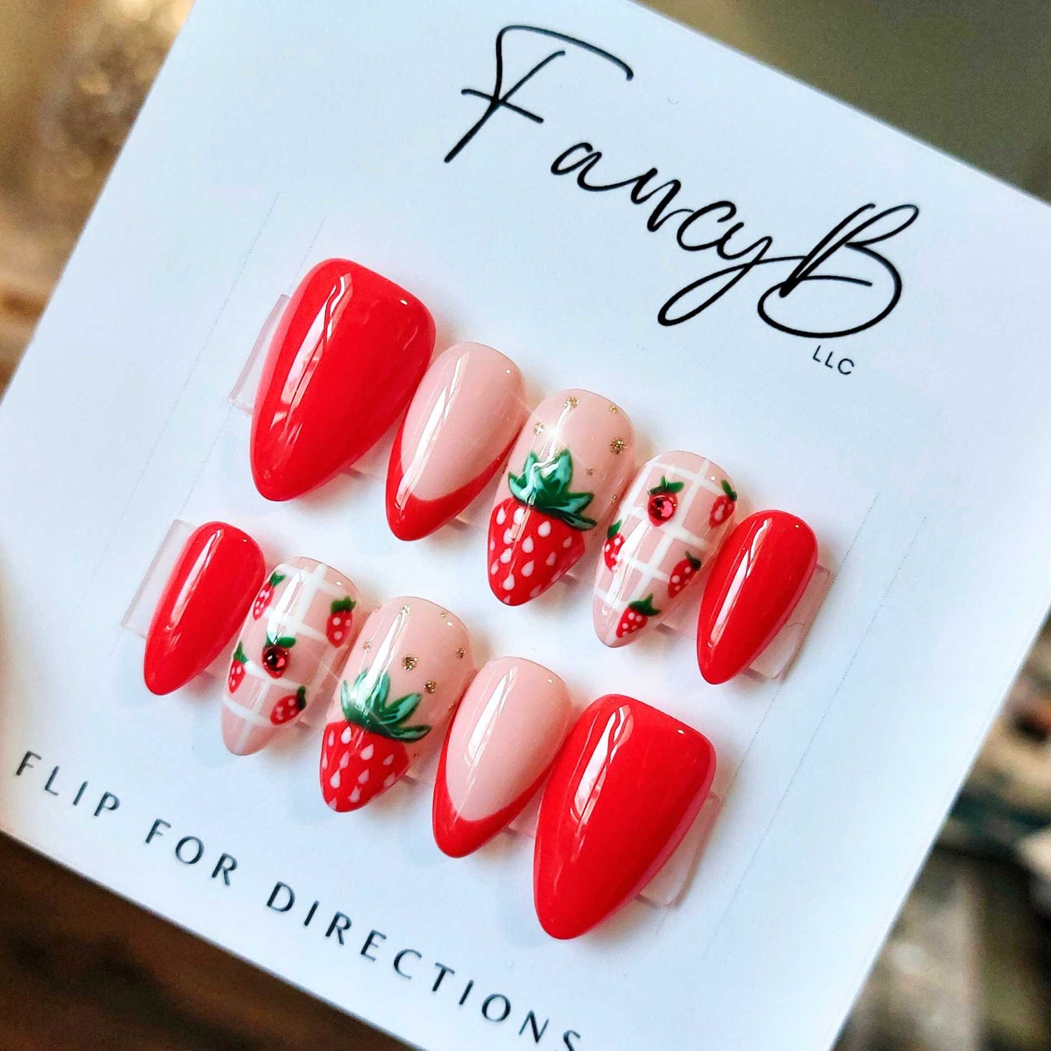 custom strawberry nails, summery fruit nails with strawberries and bright red french accents, gold glitter, and short almond shape from FancyB handmade nails.
