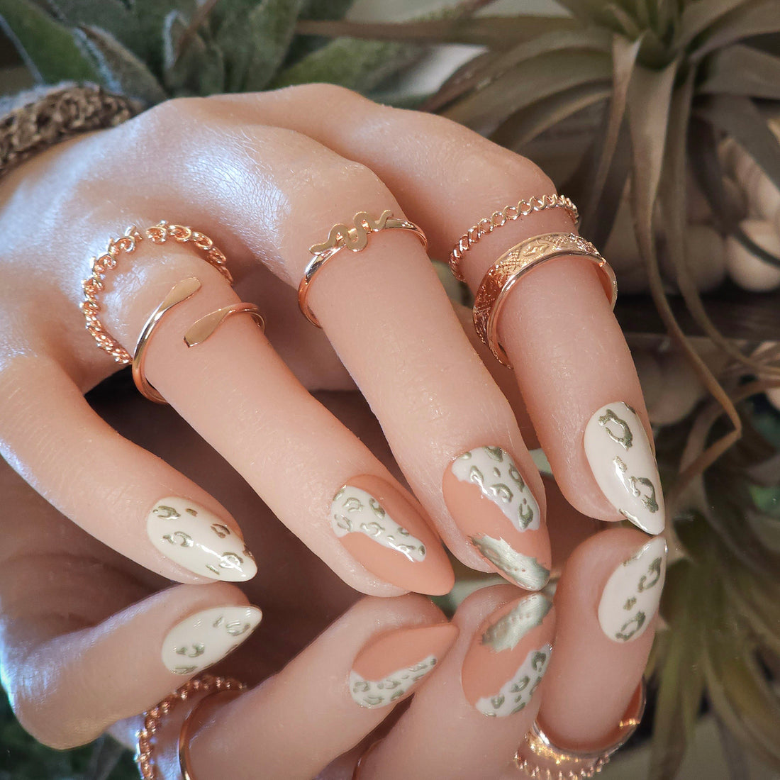 Leopard safari press on nails with metallic champagne gold leopard print, clay red and off-white gel, shown in short almond.