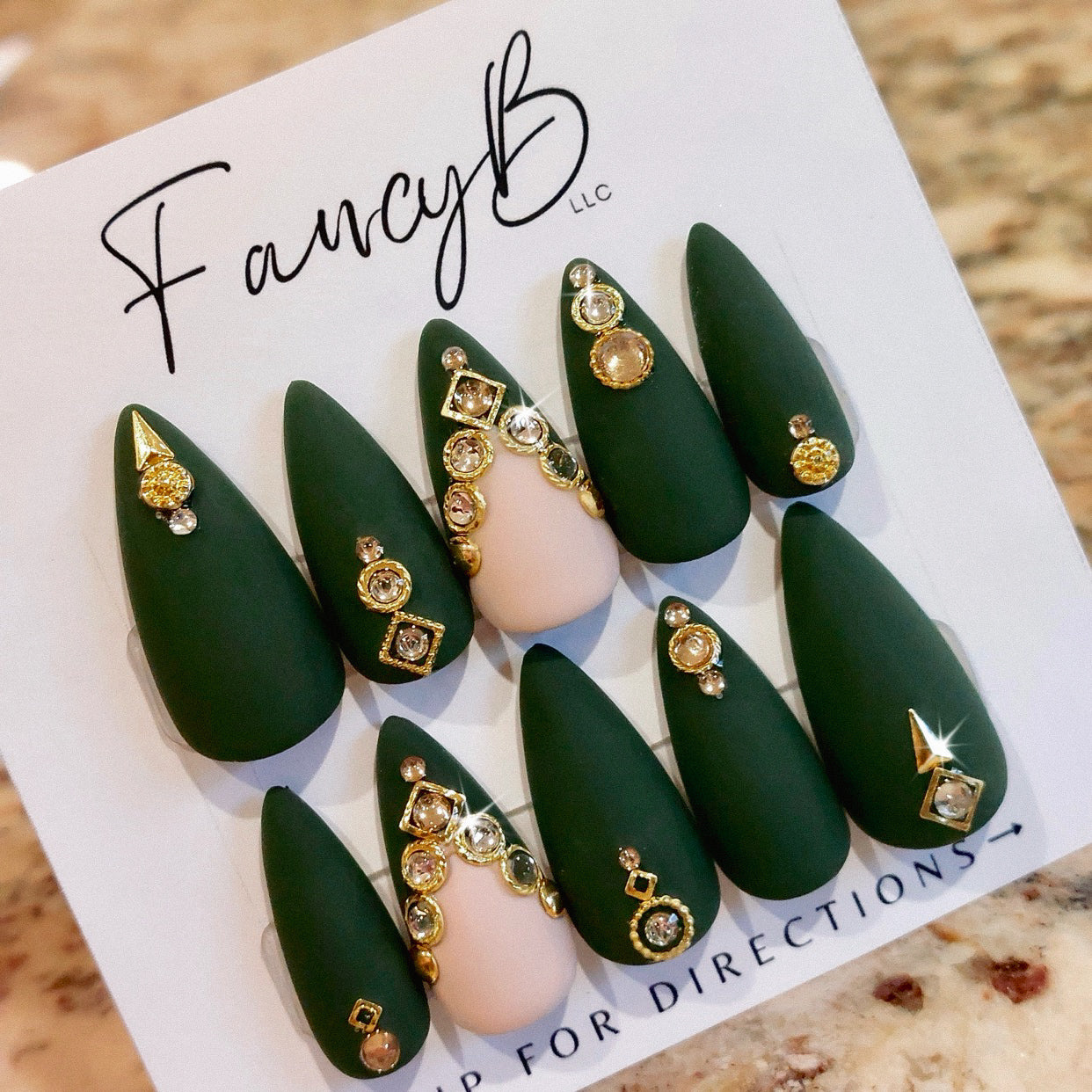 Custom press on nails - matte green with gold and champagne gems, v-french accent nail, gold decorative pieces and stiletto nail shape.