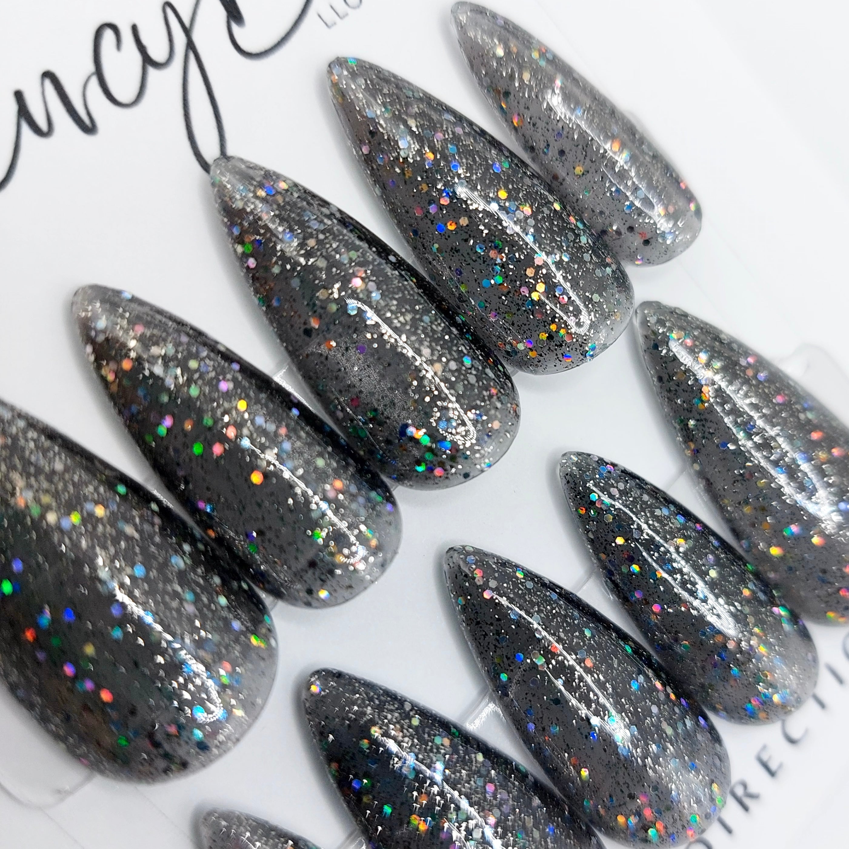 Custom press on nails in a black glitter jelly design and a medium stiletto nail shape. FancyB Nails.