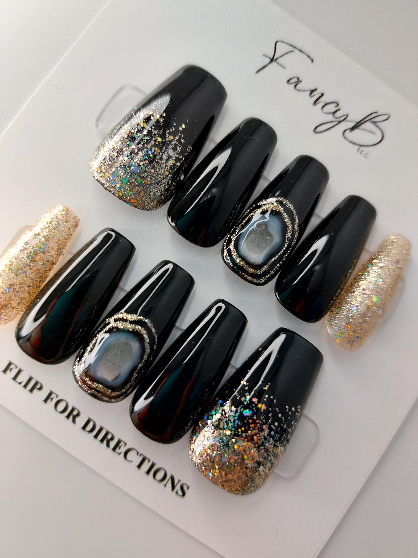 black agate press on nails with black nails and gold glitter, shown on medium coffin nails.