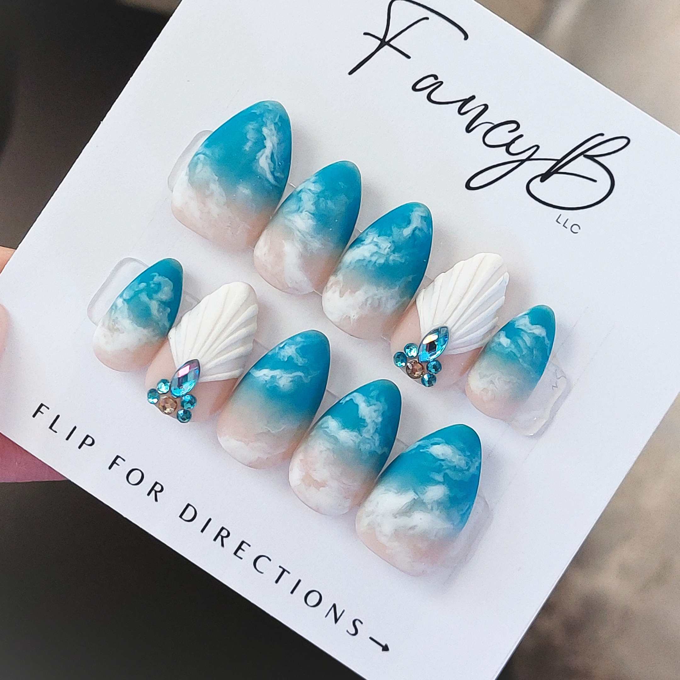Custom beach nails, ocean waves nail design with blue waves and white 3d seashell nail with blue gems. custom handmade nails by fancyb nails.