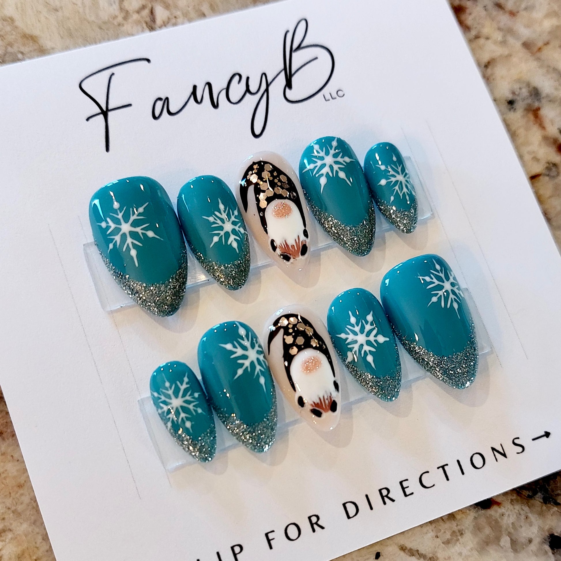 Custom press on nails gnome nails with snowflakes and glitter french tips on teal in a short almond shape. Winter snowflake press on nails fancyb nails.
