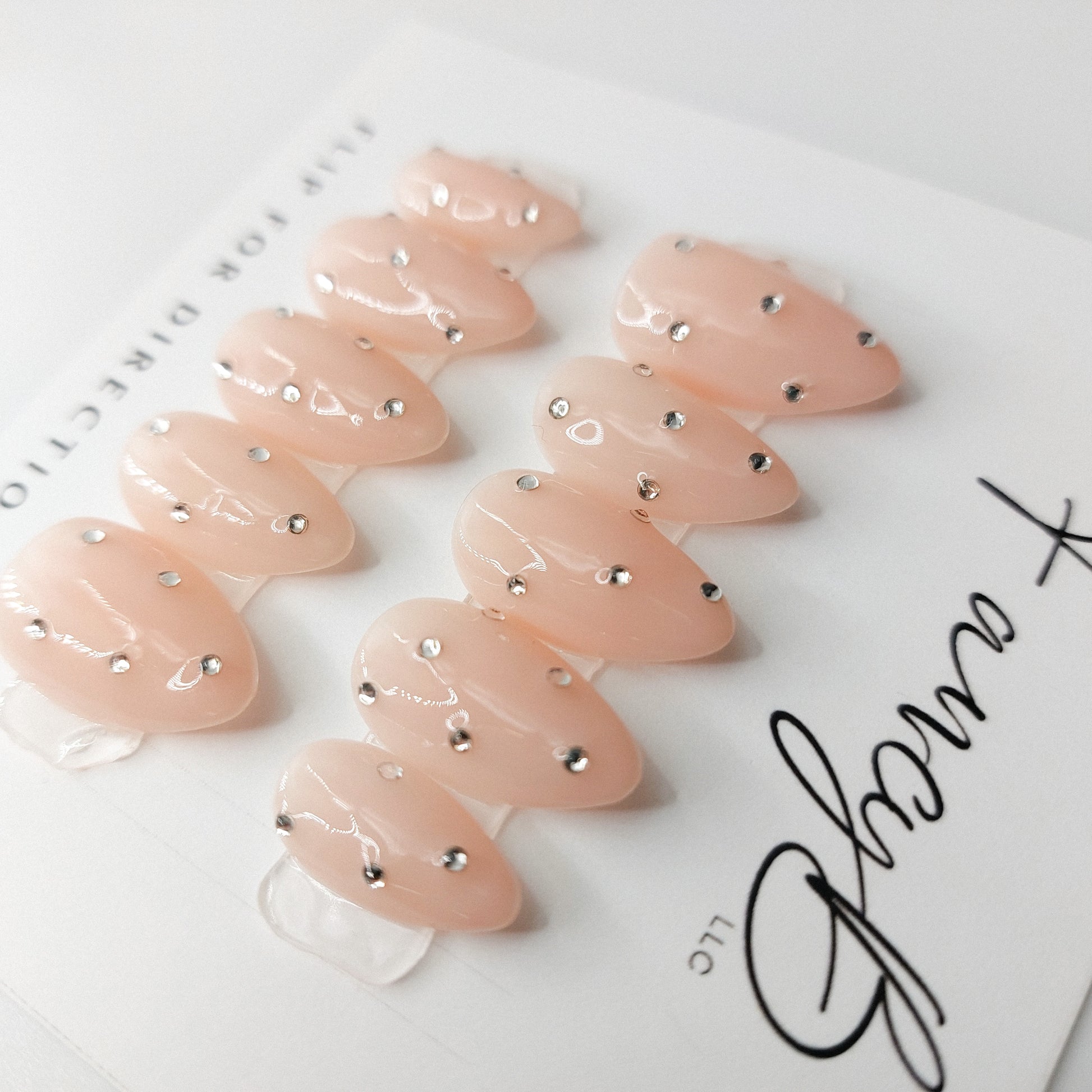 Nude jelly gel press on nails with tiny diamond gems on an almond shape.