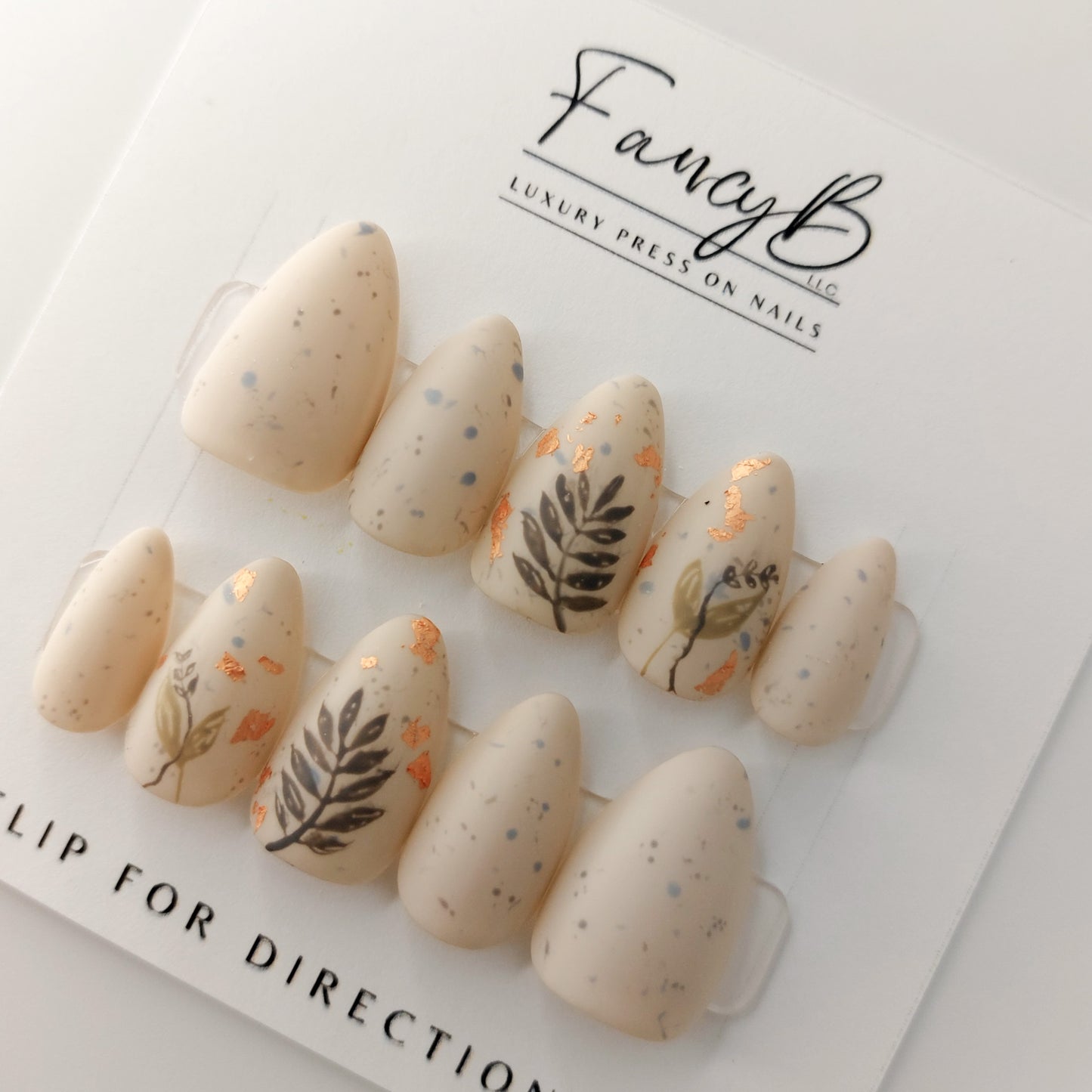Custom press on nails, fall design in short almond press on nails with almond color and specks, hand painted leaves and rose gold flakes.