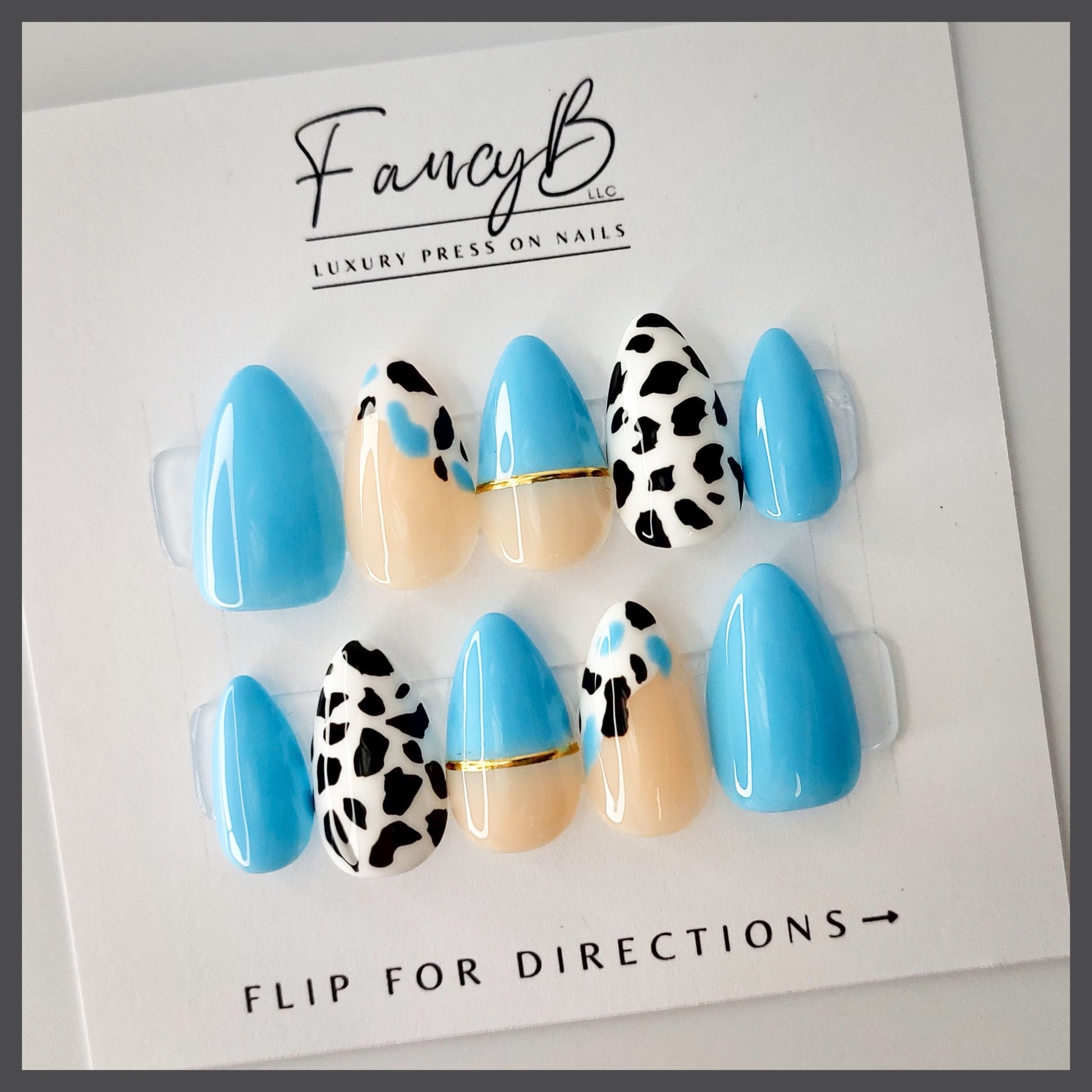 Custom press on nails, baby blue and hand painted cow print with nude and gold. FancyB nails.