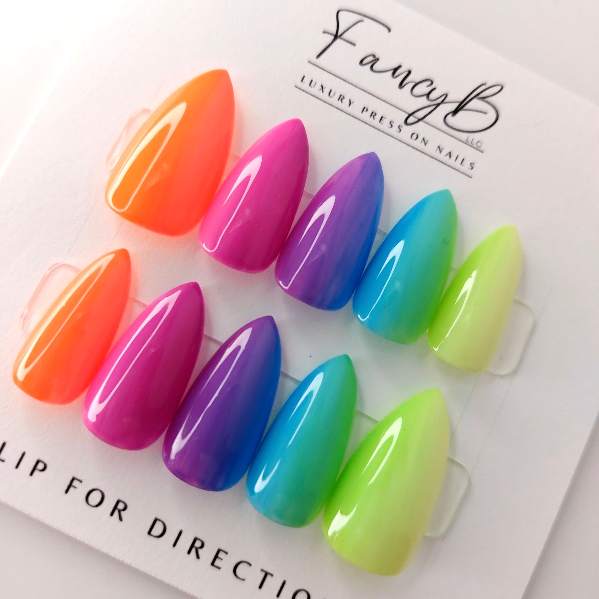 Custom press on nails in a rainbow ombre press on nails in vivid neon colors, shown in short stiletto sharpened shape. Custom nail set.