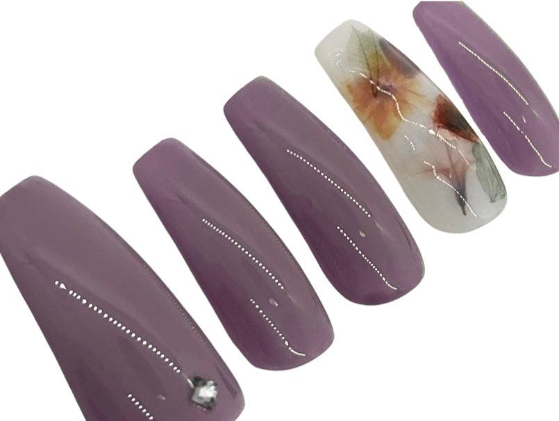 Lavender milk bath press on nails with a milky white accent nail with leaves and flowers. Shown in a long coffin/ballerina shape.