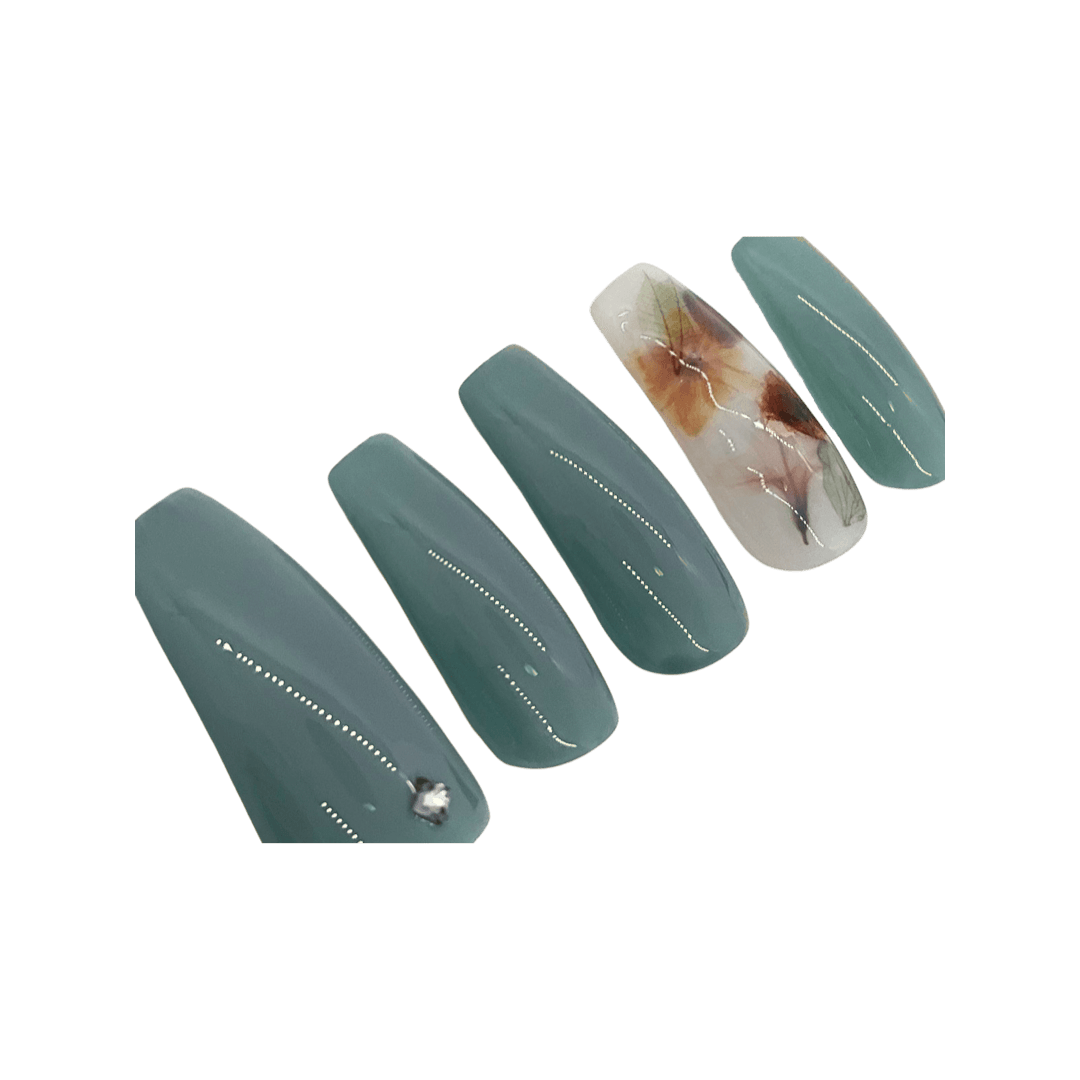 Ocean Blue milk bath press on nails with a milky white accent nail with leaves and flowers. Shown in a long coffin/ballerina shape.