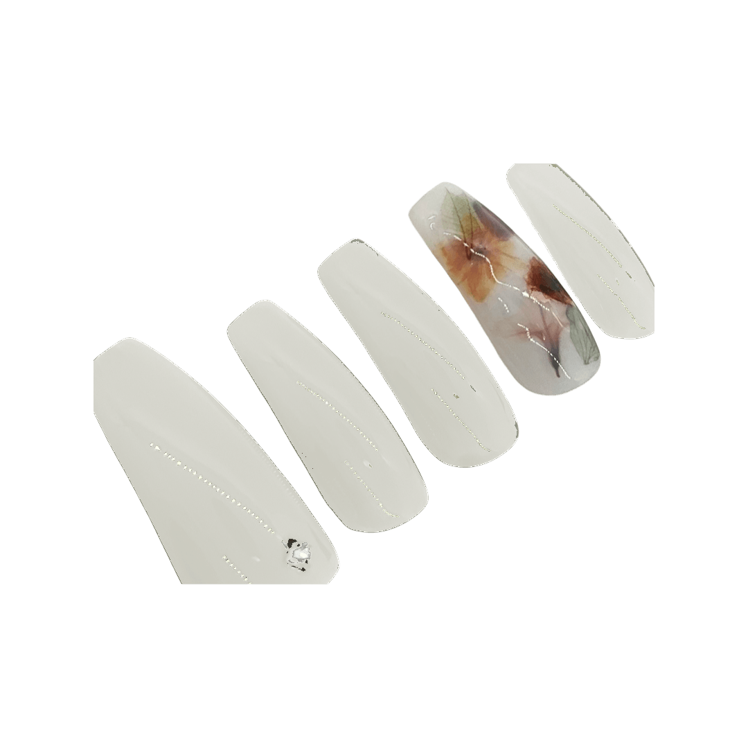 White milk bath press on nails with a milky white accent nail with leaves and flowers. Shown in a long coffin/ballerina shape.