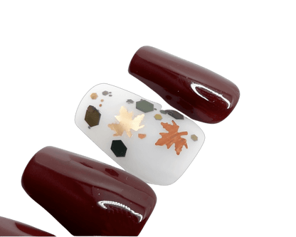 Sexy fall press on nails in a deep wine red with gold flakes and gold leaves, with a semi-transparent matte accent nail. Shown in a short coffin shape.