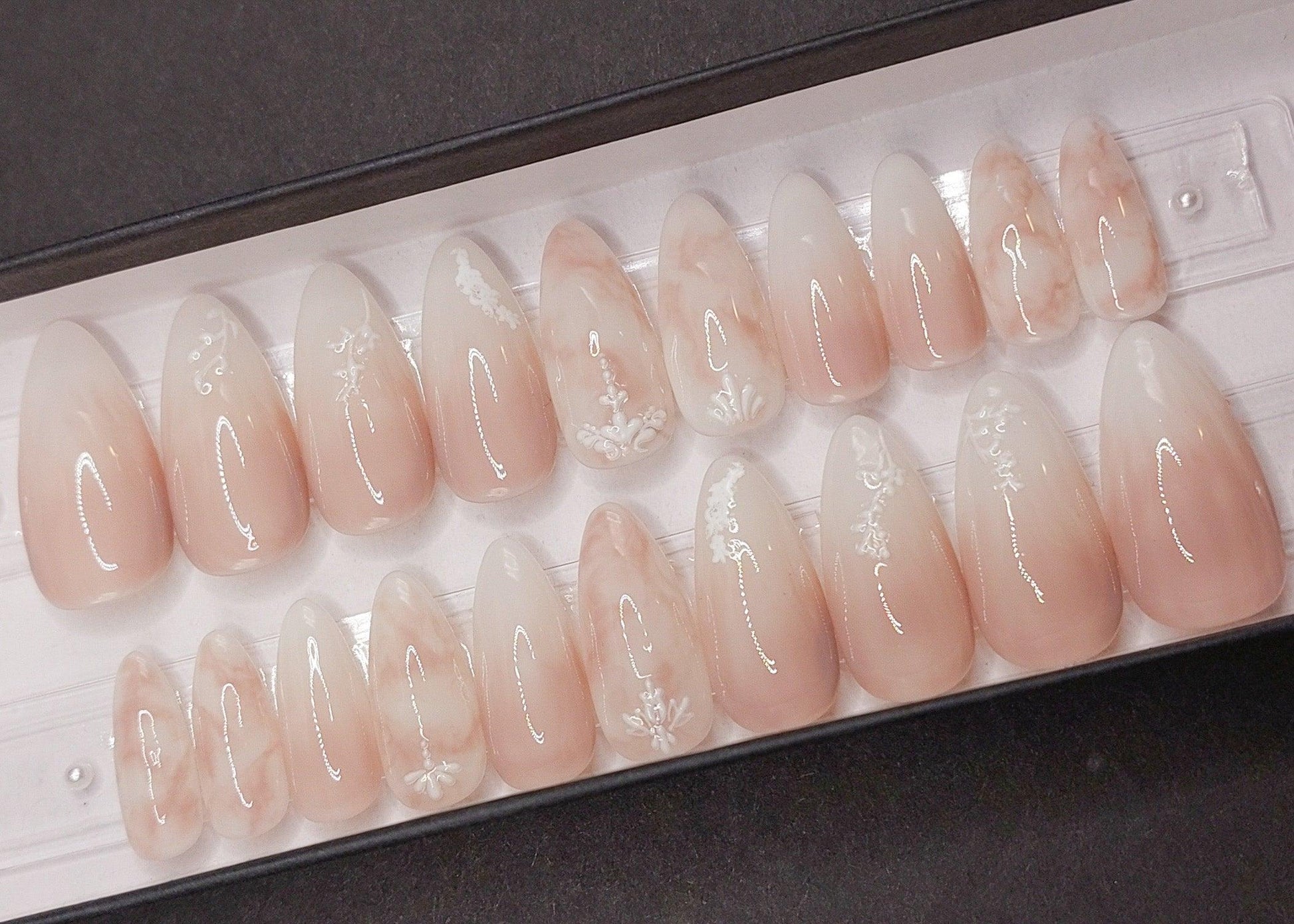 These beautiful press on nails are a soft rose color with pink and milky white ombre nails, marble nails, and 3d florals. Shown in a long almond shape.