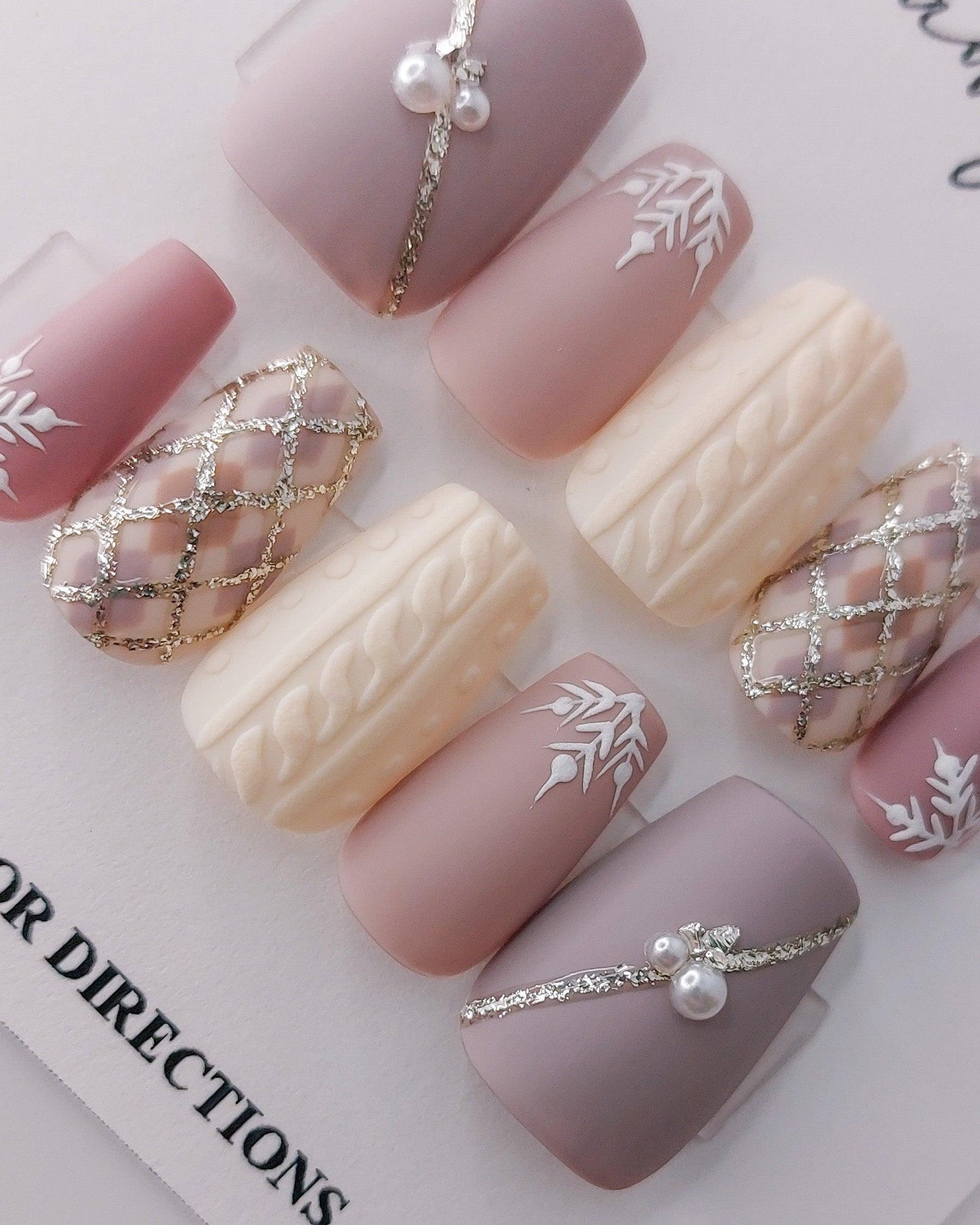 Custom Press on Nail Design. Light mauve purples with hand drawn white snowflakes, plaid with glitter, 3d sweater nail, silver glitter lines, and pearls.